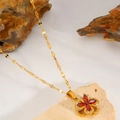 Detailed macro of gold rotating flower necklace with red gemstone clover petals - Red