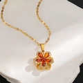Macro shot of gold floral necklace with orange teardrop gemstone on white stone background - Red Zirconia Flower Pendant Necklace