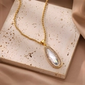 Gros plan d'une chaîne torsadée dorée avec pendentif en cristal sur fond de pierre - Style Goutte d'Eau / Collier Goutte Or Zirconium Transparent
