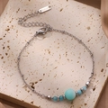 Détail d'un bracelet en acier titane avec perles colorées et étiquette en métal S.stuel - Bleu