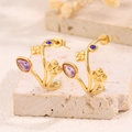 Gros plan de boucles d'oreilles fleurs en C avec pierres violettes et cristaux bleus - Style Trèfle à Quatre Feuilles