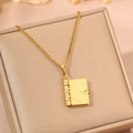 Detail view of a vintage gold book locket necklace with floral engraving and quotes - Gold