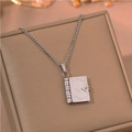 Close-up of vintage book locket necklace with inspirational text on jewelry box - Silver