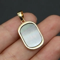 Detail of a rectangular black mother of pearl pendant with gold plated rim held by hand - Pendant Only (Without Chain) - Black Mother of Pearl