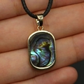 Macro detail of rectangle shell pendant with gold rim and iridescent colorful abalone luster - Abalone Shell Necklace
