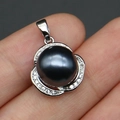 Close-up of black pearl pendant with luxury clover leaf diamond setting in hand - Iridescent Black
