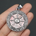Close-up of a pink yin yang bagua pendant made of shell and alloy held by hand - 29x39mm / No. 2 Pendant