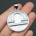 Silver Libra zodiac pendant with white shell inlay held by hand for size reference - 32x37mm / Libra