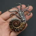 Macro-opname van een ammoniet fossiele hanger met zilveren octopus detail in de hand - Stijl 1 (Alleen Hanger (Zonder Ketting))