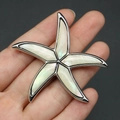Vista de mano de un gran broche de estrella de mar con incrustación de nácar natural - 52x54mm / Madreperla Blanca