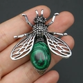Détail macro d'une broche en forme d'abeille avec malachite, tenue à la main pour l'échelle - 42x47mm / Malachite