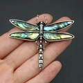 Macro shot of dragonfly brooch with abalone shell wings held by hand for scale - Abalone Shell (Multicolor)