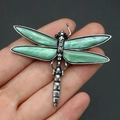 Detail of silver dragonfly brooch with green shell inlay held against black background - Mother of Pearl White (No. 3)
