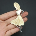 Detalle de una mano sosteniendo un broche de bailarina con nácar de abulón irisado - Estilo 3