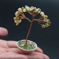 Gros plan d'un arbre de vie en citrine fait main dans un pot blanc tenu à la main - Citrine