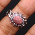 Detailopname van een ring met roze natuursteen, zonnestraalframe en gevlochten zilveren band - Rhodoniet