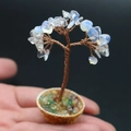 Mini árbol de cristal con piedras blancas en una pequeña cesta sostenida en mano - Ópalo