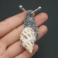 Scher-Brosche in Schneckenform aus silbernem Metall mit Naturmuschel und braunen Flecken - Ostwind-Schnecke Brosche / Silber
