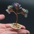 Miniature crystal tree of life with colorful natural stones held in a palm for scale - Fluorite