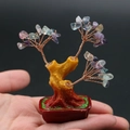 Mini-Edelsteinbaum mit bunten Kristallblättern auf einer Handfläche präsentiert - Fluorit