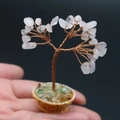 Miniature pink quartz crystal money tree in a brown basket base, held in palm - Rose Quartz