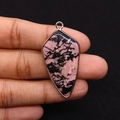 Detail of pink rhodonite stone pendant with gold plated edge held in hand - Rhodonite