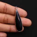 Detail of water drop black stone pendant with gold metal rim held by fingers - Black Agate