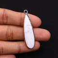 Detailed close-up of a teardrop-shaped white stone pendant with golden metal edges - Howlite