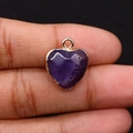 Gros plan d'un pendentif en pierre violette taillée en cœur avec bords dorés polis - Améthyste