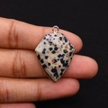 Close-up of Dalmatian Jasper stone pendant with rose gold plating held in hand - 22x30mm / Dalmatian Jasper