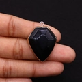 Macro view of shield-shaped black natural stone pendant with gold plated edge and hook - 22x30mm / Black Agate