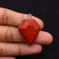 Close-up of shield-shaped red jasper stone pendant with faceted surface and silver trim - 22x30mm / Red Jasper
