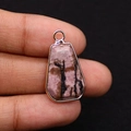 Macro shot of a trapezoid pink rhodonite stone pendant with rose gold plated metal trim - Rhodonite with Black Lines