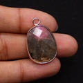 Faceted pear-shaped red stone pendant with rose gold plating, held in hand for size - 17x26mm / US 8