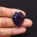 Handheld view of a shield-shaped purple natural stone pendant with gold plating - 22x30mm / Purple Crystal