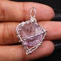 Nahaufnahme eines handgefertigten, drahtumwickelten lila Kristallanhängers in der Hand - 20-30 mm / Amethyst