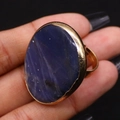 Dettaglio macro di un anello dorato regolabile con una grande pietra naturale blu ovale - 30x41mm / Lapislazzulo