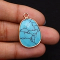 Oval turquoise pendant with gold plated edges shown held by hand for scale - 17x26mm / Blue Turquoise