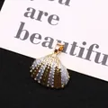 Macro detail of bicolored metallic shell pendant with gold edging and striped texture - Gold Silver Two Tone Texture