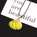 Détail du pendentif coquillage jaune avec bordure dorée sur une carte de présentation - Rayé Jaune