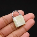Macro shot of a light green jade lock pendant with a silver metal clasp held in hand - Ivory Jade