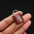 Macro view of natural stone handbag pendant held by fingers to show compact size - Swan Stone