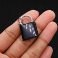 Miniature black obsidian lock pendant held between fingers showing its small size - Black Agate