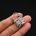 Macro shot of dalmatian jasper stone lock pendant held between fingers with metal ring - Dalmatian Jasper
