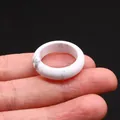 Polished white marble stone ring with natural grey veins shown on hand against black backdrop - Howlite