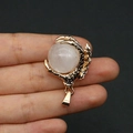 Detailed view of a gold-plated dragon claw pendant holding a natural pink gemstone bead - White Crystal
