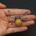Detailed spider pendant featuring a large yellow gemstone held in a hand for size scale - 34x47mm, 14g / Topaz