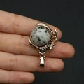 Macro shot of a golden dragon claw pendant holding a grey spotted natural stone bead - Azurite