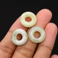 Drei grün-weiße Naturstein-Donut-Anhänger an den Fingern für die Größenperspektive - 16mm / Xinschan Jade