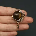 Golden dragon claw pendant holding a brown tiger eye stone sphere held by hand - Tiger's Eye